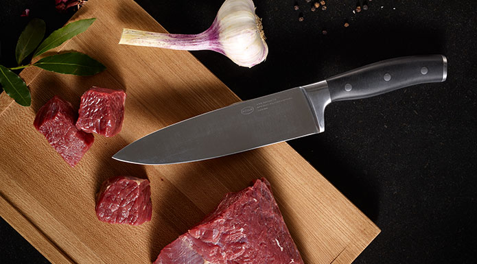 Tradition series chef's knife on cutting board with cut meat