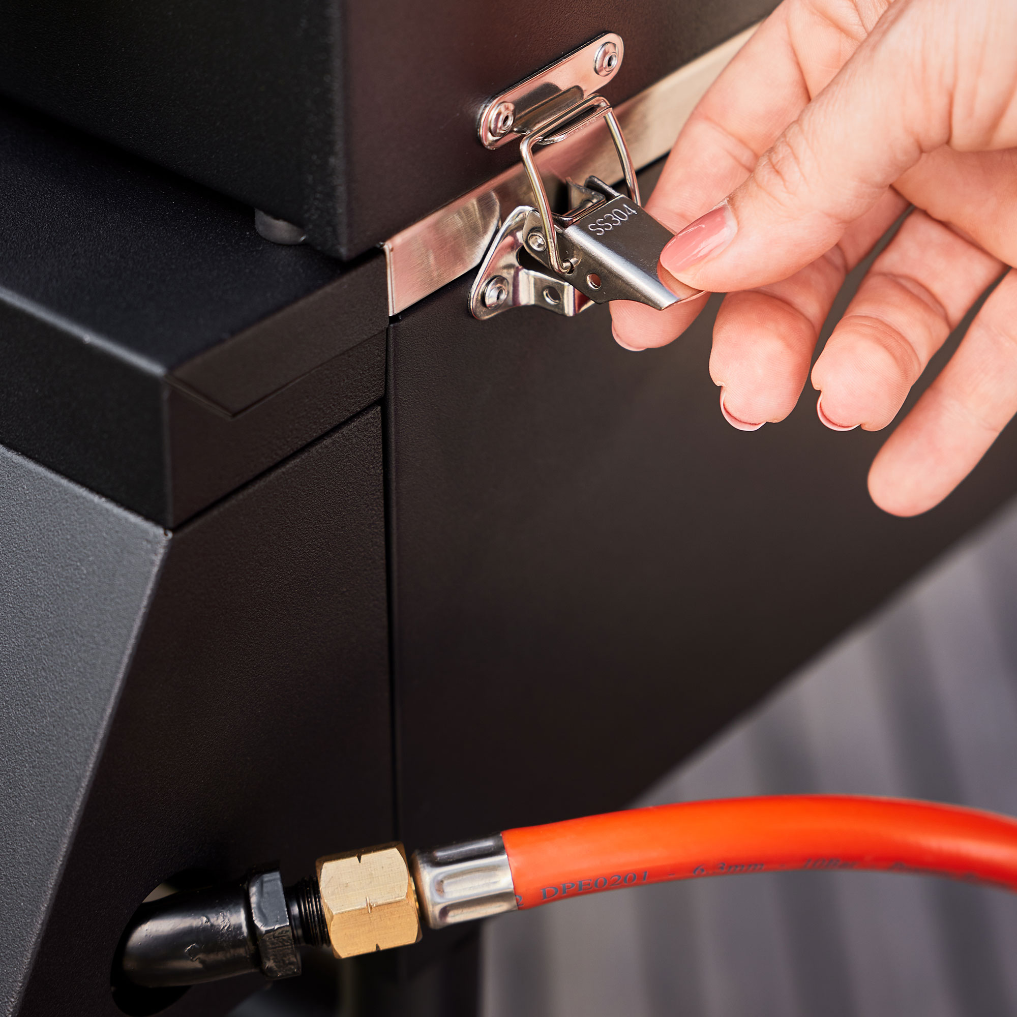 RÖSLE Gasgrill Videro Portable PRO G2-P - Verschlussöffnung Gasgrill Videro Portable PRO G2-P mit einer Hand, die den Verschluss öffnet.