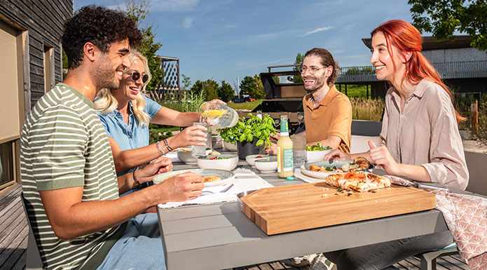 Pizza Vier Freunde sitzen zusammen am Terrassentisch und essen zusammen Pizza