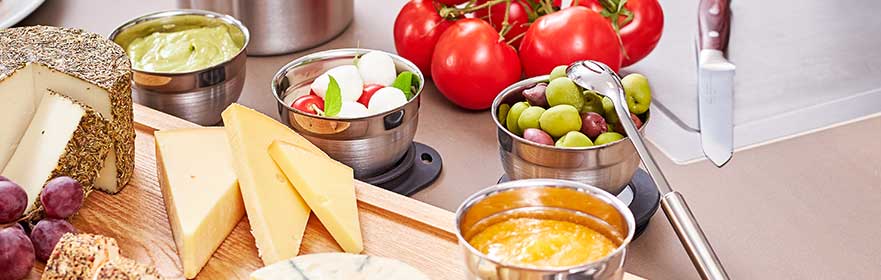 Schaaltjes van RÖSLE met verschillende hapjes Schaaltjes met olijven, kerstomaatjes, kaas en dipsaus op tafel zetten.